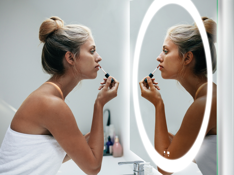 girl looking at her reflection in a Slique lighted mirror as she brushes her teeth